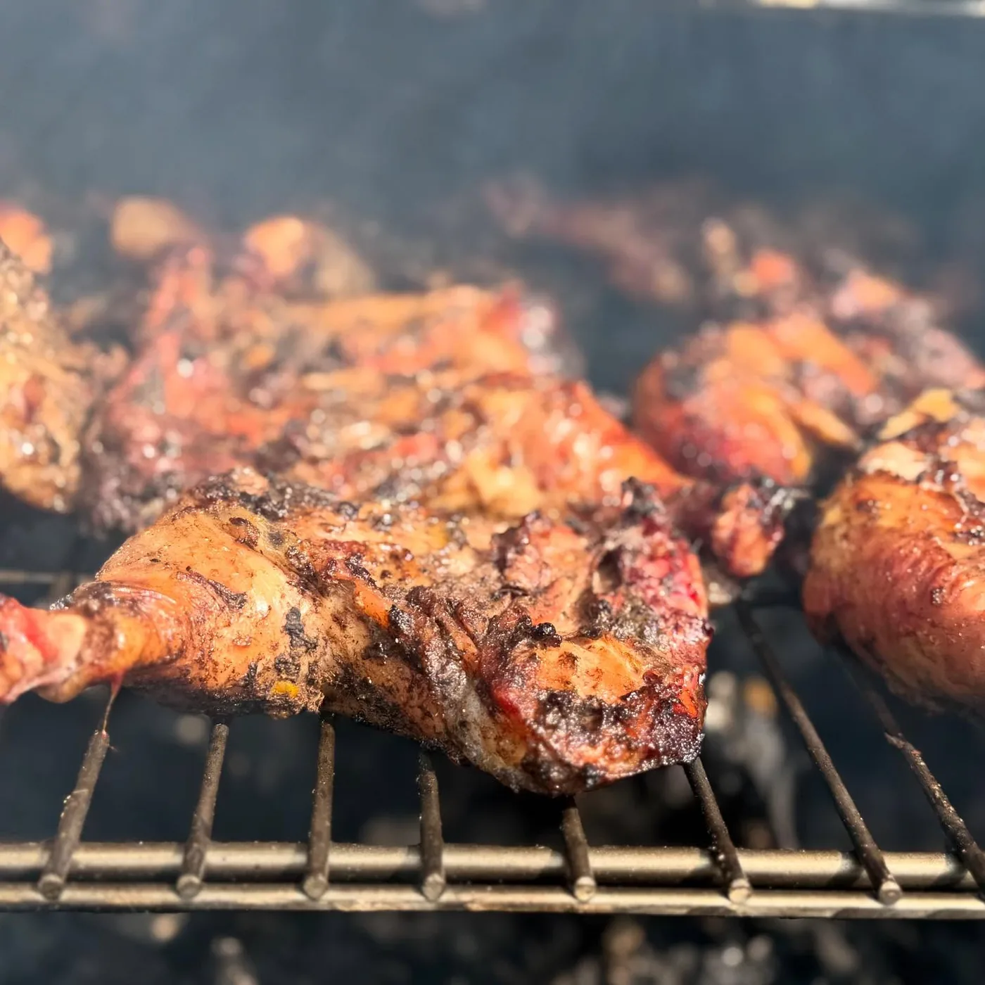 Jerk chicken smoking on the grill